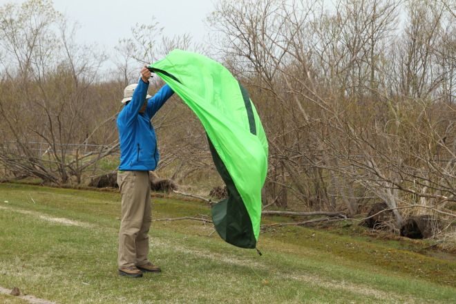 風に背を向けてテントを広げる